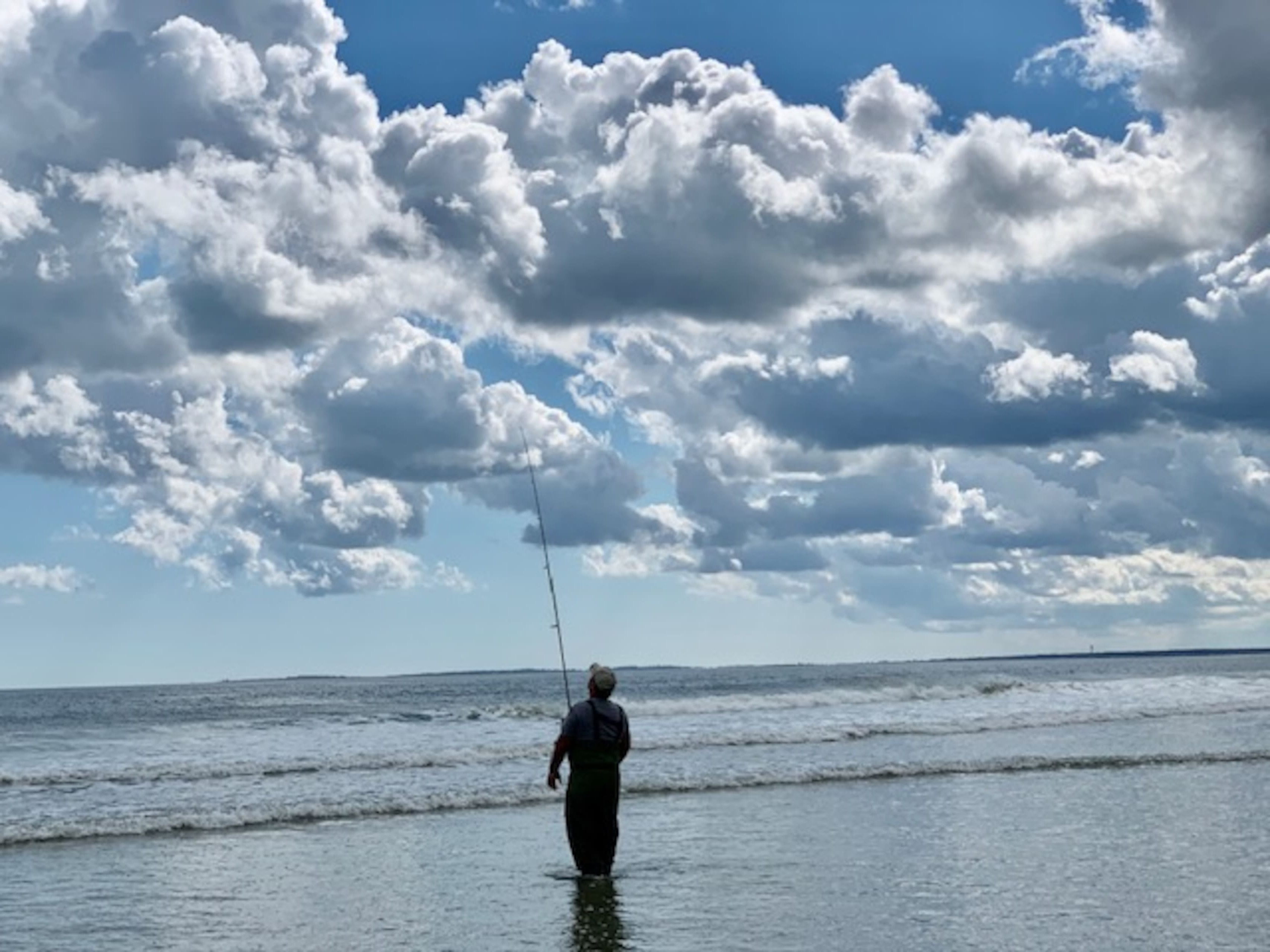 Fisherman casting under a cloudy sky