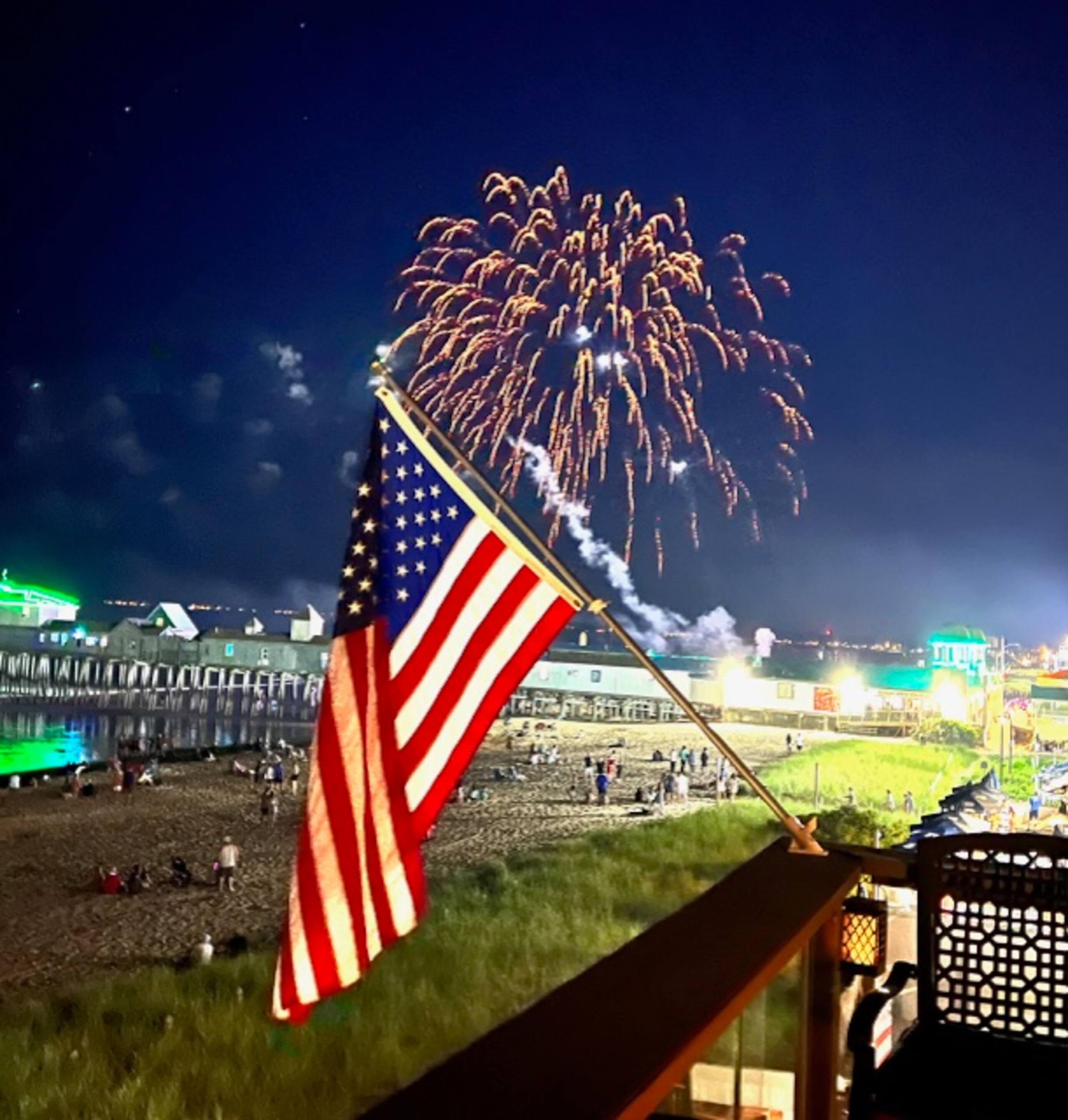 American flag with fireworks over the pier at night