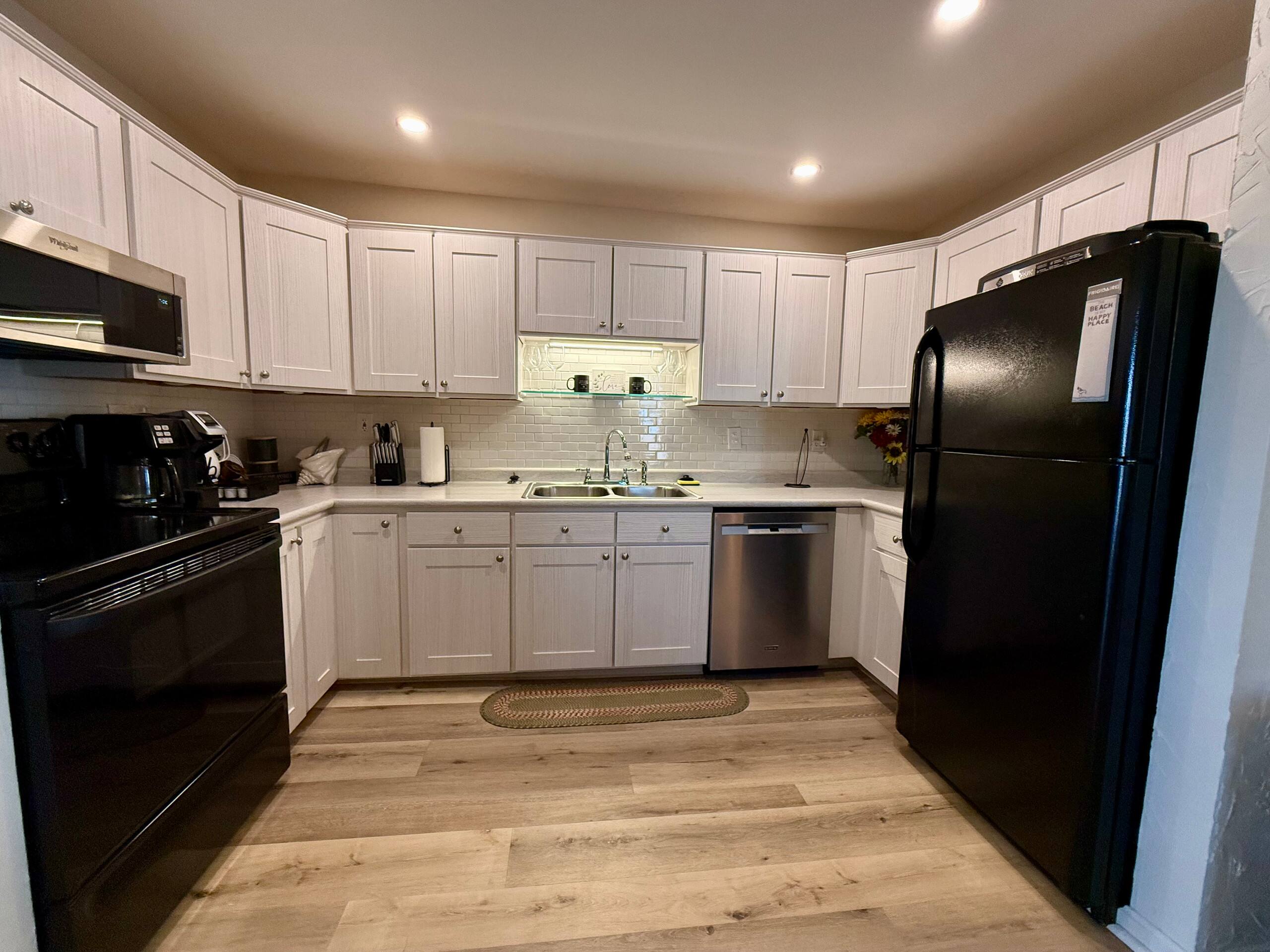 Full kitchen with white cabinets and black appliances