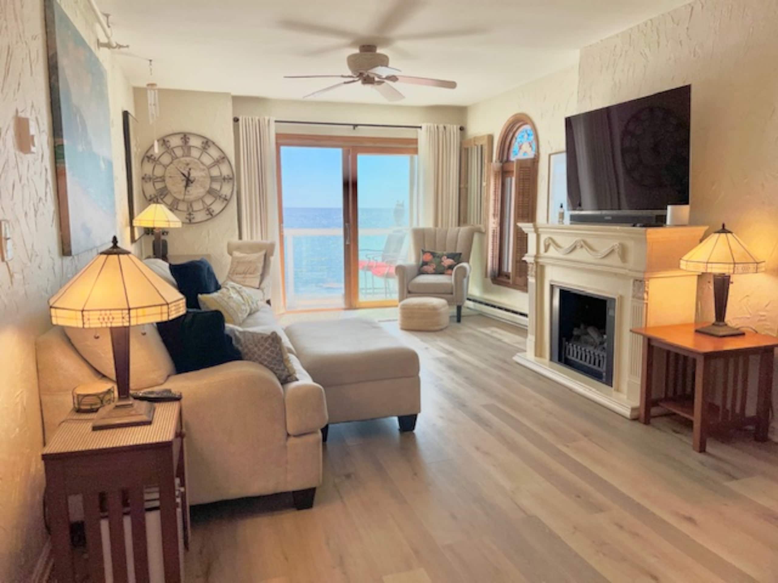 Living room with fireplace and sliding glass door open to the ocean-view deck